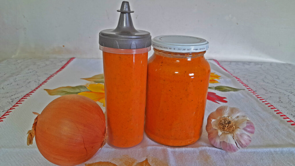 Molho de pimenta dedo de moça caseiro sendo despejado em um pote de vidro para armazenamento na geladeira.